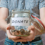 foto de un niño caucasico sosteniendo un frasco de monedas para hacer una colecta en beneficio de una institución que requiere una donación