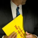 foto de la silueta de un hombre vestido como ejecutivo con corbata azul, mientras guarda un sobre amarillo que dice información confidencial en su saco